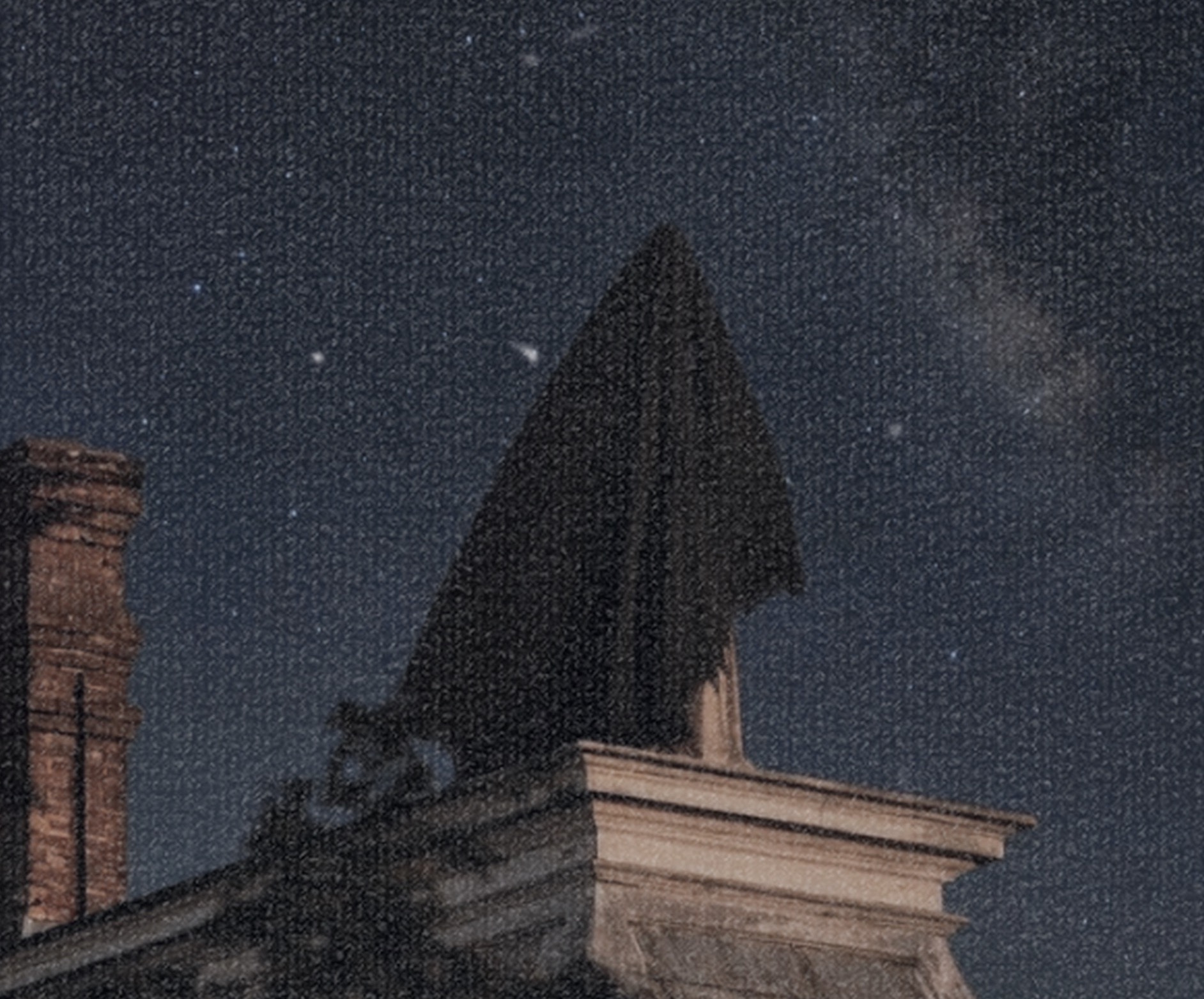 Hooded figure silhouetted on a rooftop beneath a starry night sky